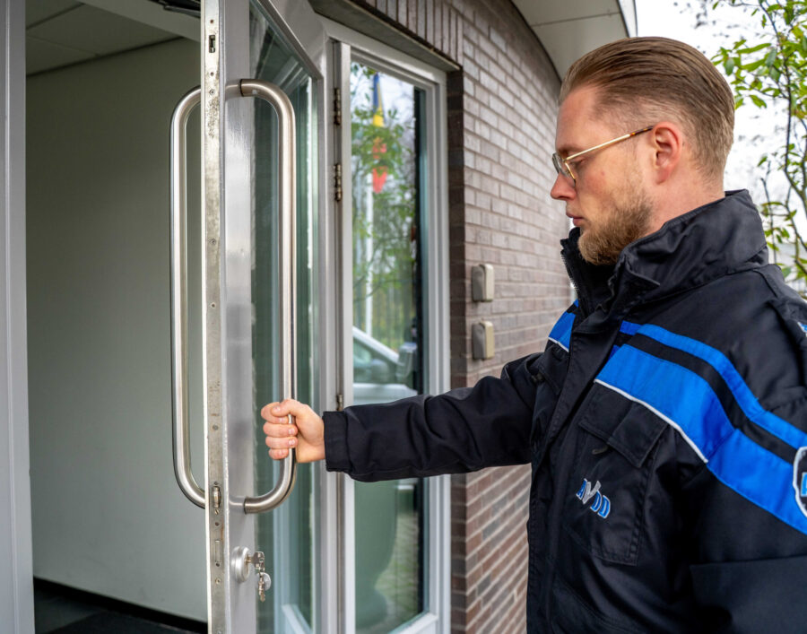 Beveiliger van AVDD Beveiliging beveiligingsbedrijf opent een deur open- en sluiten