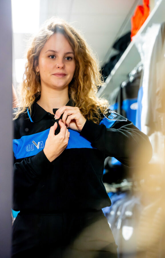 Beveiliger van AVDD Beveiliging vrouw doet kleding aan van het beveiligingsbedrijf voor de spiegel