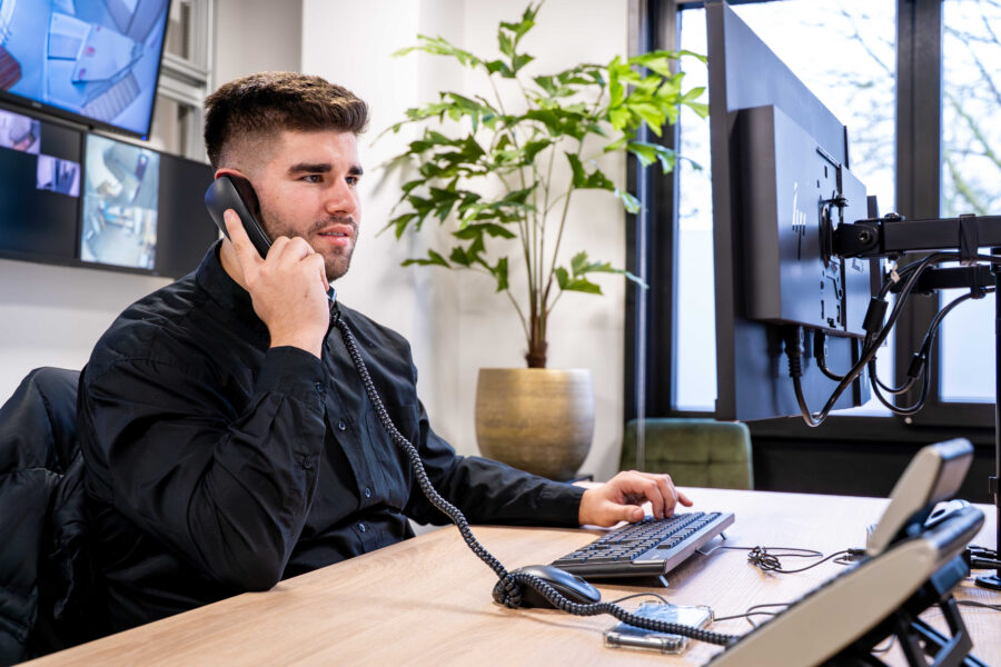 Mannelijke medewerker van AVDD achter het bureau aan de telefoon