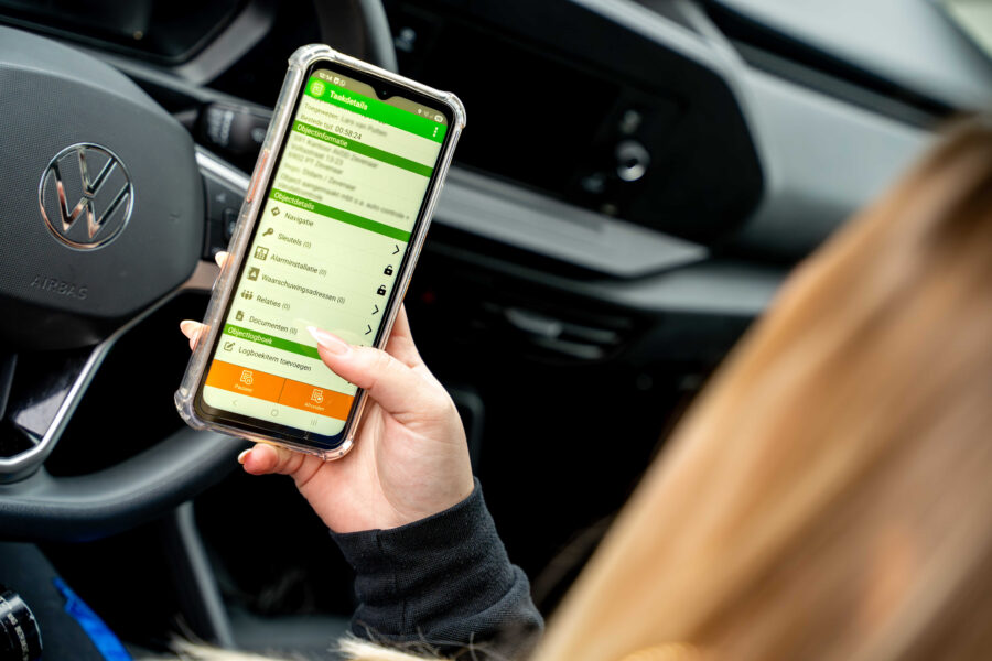 Beveiliger met telefoon in de hand bekijkt binnengekomen melding en taak